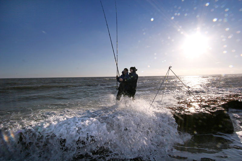 Two anglers stand in the breaking waves